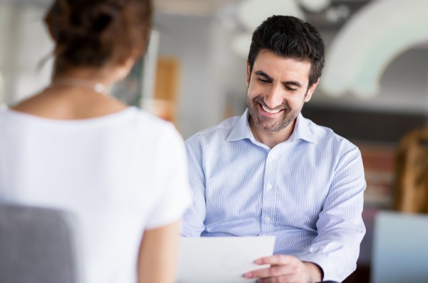 A professional male consultant in a modern office environment smiling while reviewing financial planning documents with a colleague, representing the collaborative and expert advisory support provided to mission-driven organizations.
